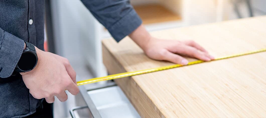 A close up of a man measuring a worktop