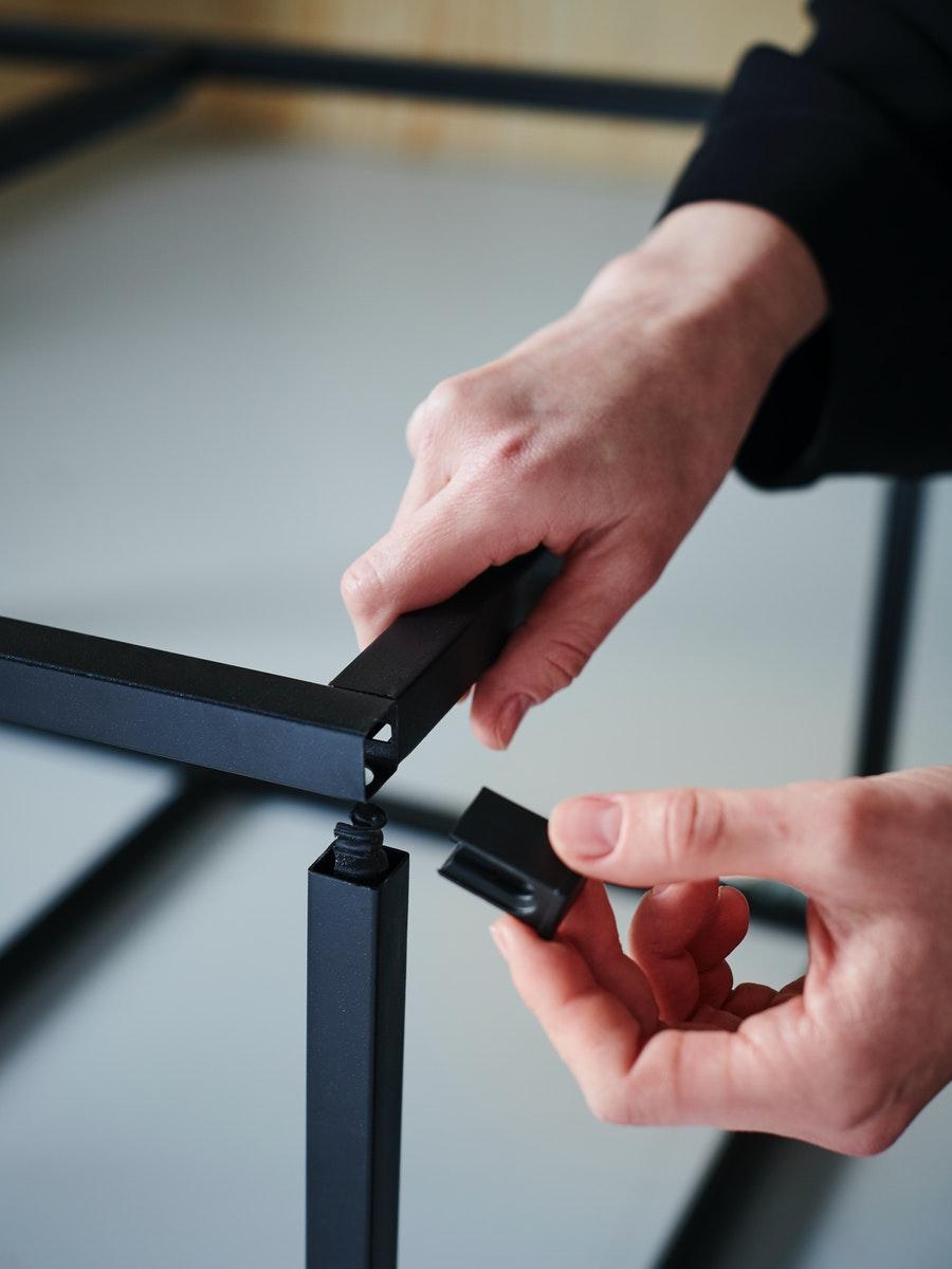 A close up of a pair of hands fixing an ENHET frame together.