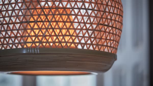 A close-up of a switched on MISTERHULT pendant lamp handwoven in the light, natural material bamboo.