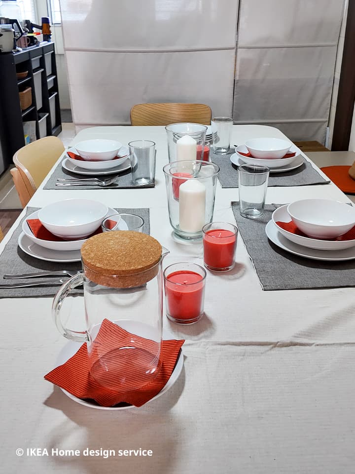 A close-up of a table setting with place mats, napkins, plates, bowls, and candles in a refreshed 3-room HDB flat in Singapore, designed by IKEA home design service