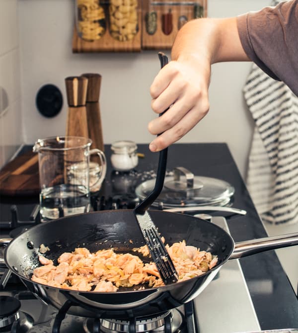 A close-up of a teenager moving food in a frying pan