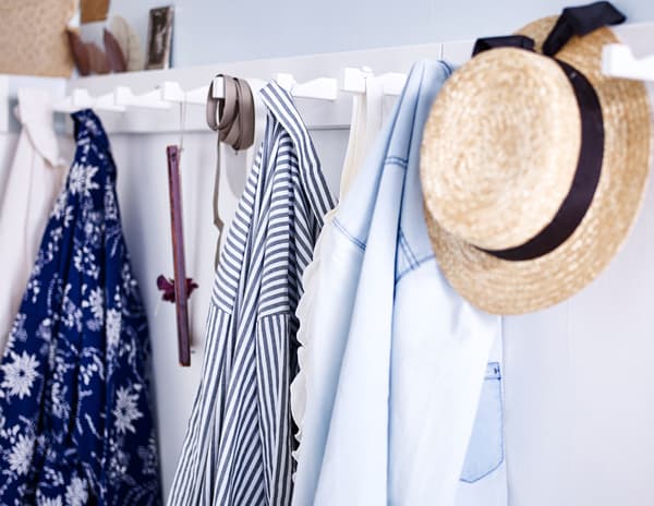 A close up of a wall rack with clothes and accessories hanging from hooks.