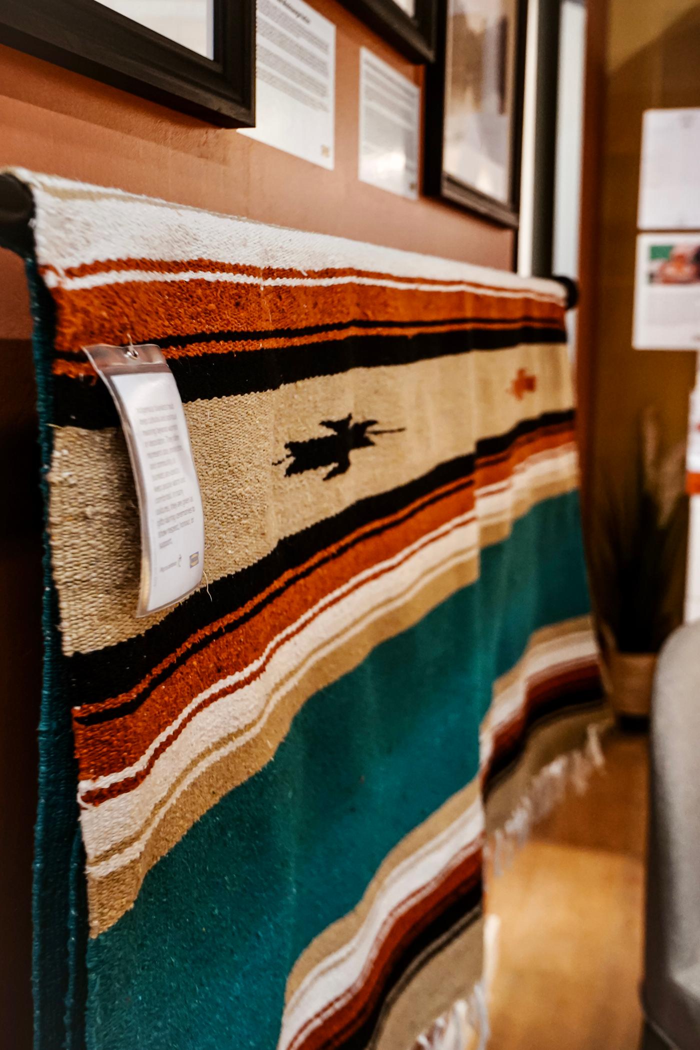 A close-up of a woven tapestry draped over a wooden stand.
