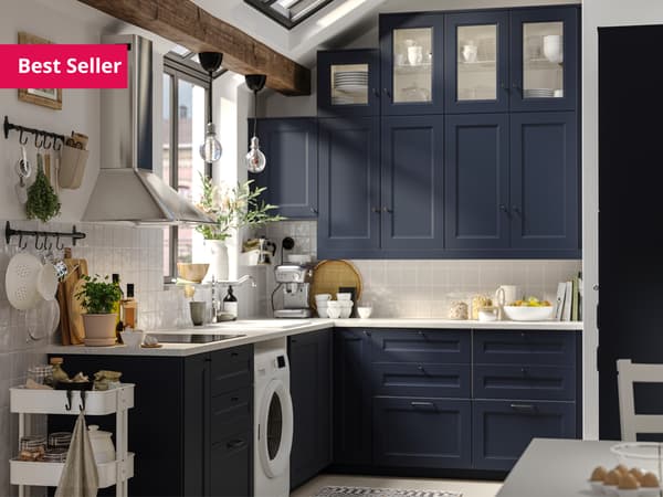 A close up of an IKEA AXSTAD blue kitchen cabinet with glass doors, white worktop and metal handles.