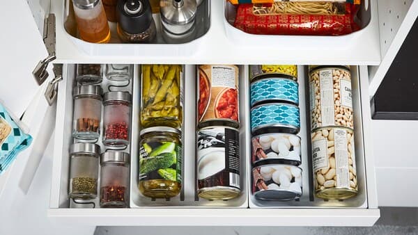 A close-up of an open drawer with cans, tins, and spices organised using VARIERA dividers.