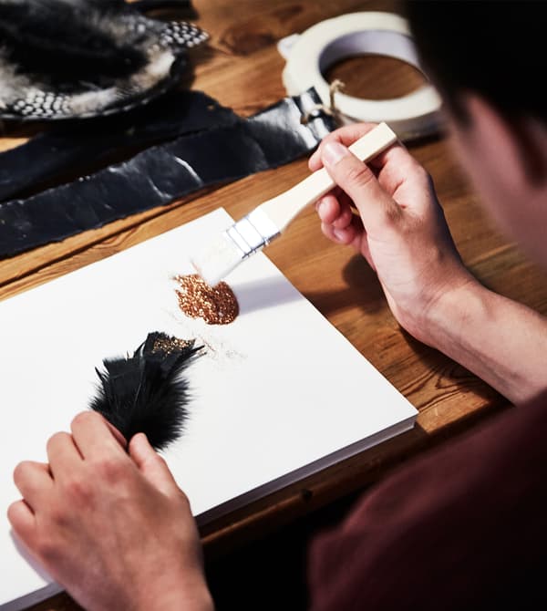 A close up of glitter being painted onto a feather.