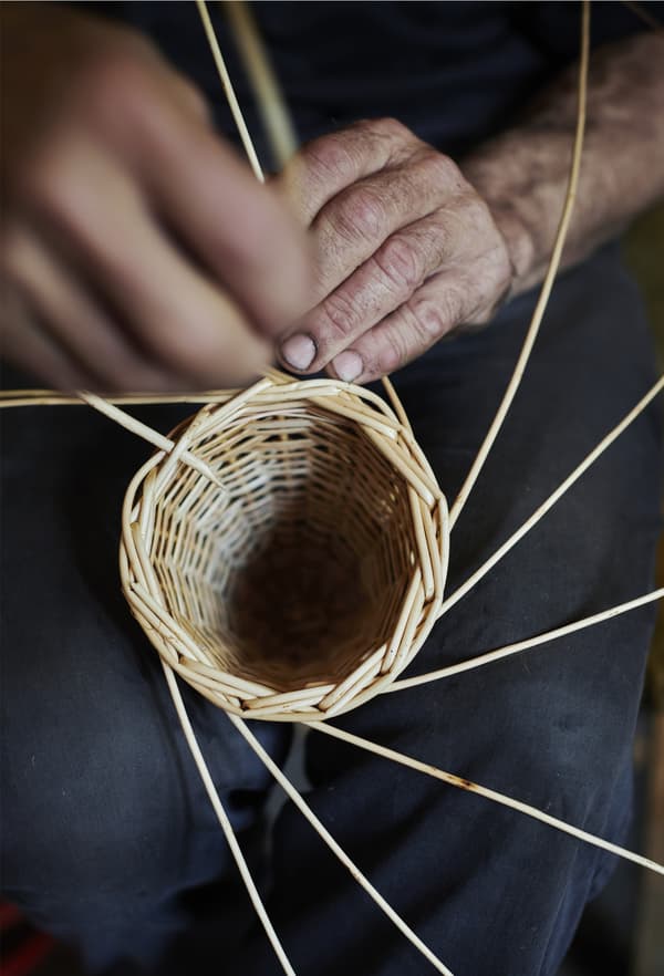 A close-up of hands weaving cane.