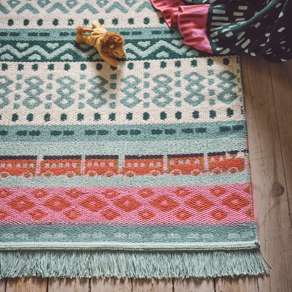A close-up of KÄPPHÄST rug with a pattern inspired by traditional Swedish mittens in green, red and pink.