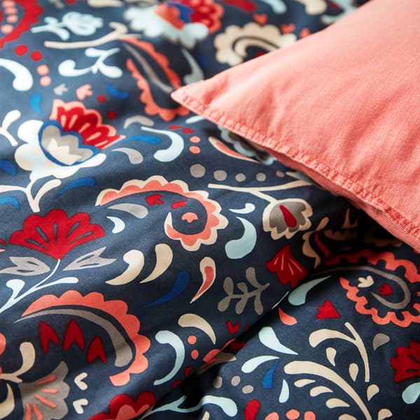 A close-up of KRATTEN quilt cover with a traditional floral pattern in many colours on a dark blue background.