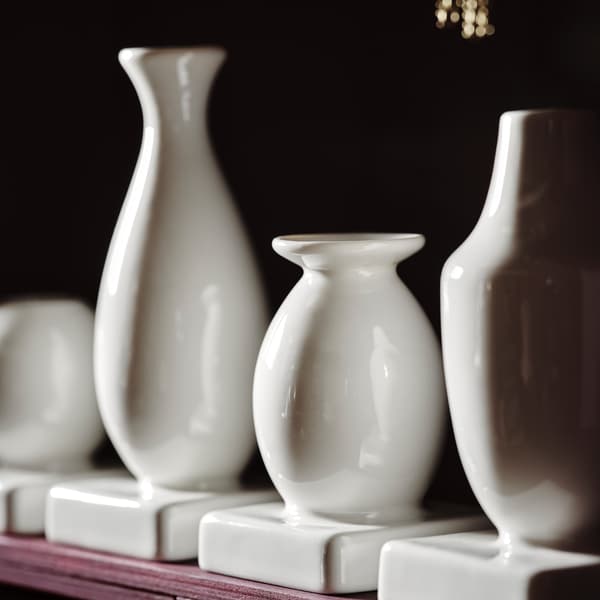 A close-up of KRINGGÅ set of four vases in different shapes and sizes made in white-glazed stoneware.