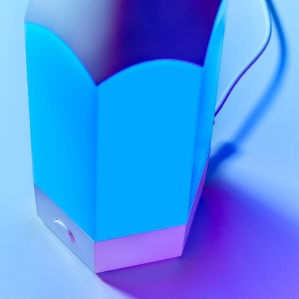 A close-up of PELARBOJ table lamp made in a playful pencil design, showing blue light coming from it.