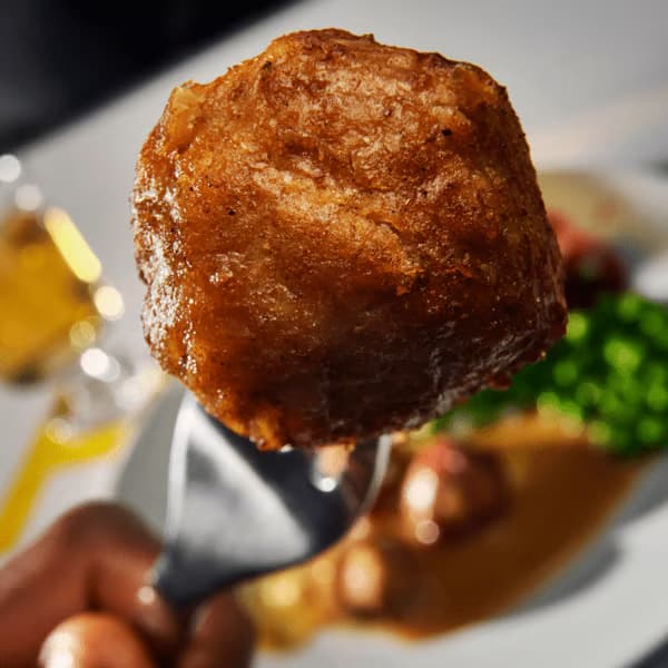 A close-up of plant ball, HUVUDROLL, with a blurred background showing a plate.