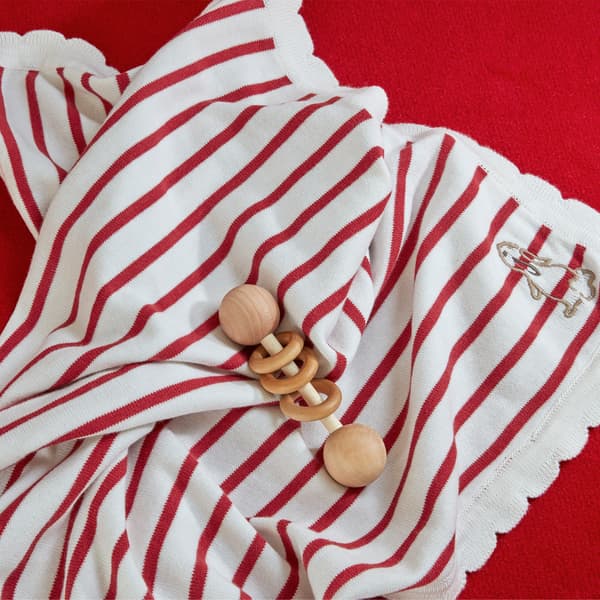 A close-up of RÖDHAKE blanket with red stripes on the light-coloured background with a rabbit in the corner.