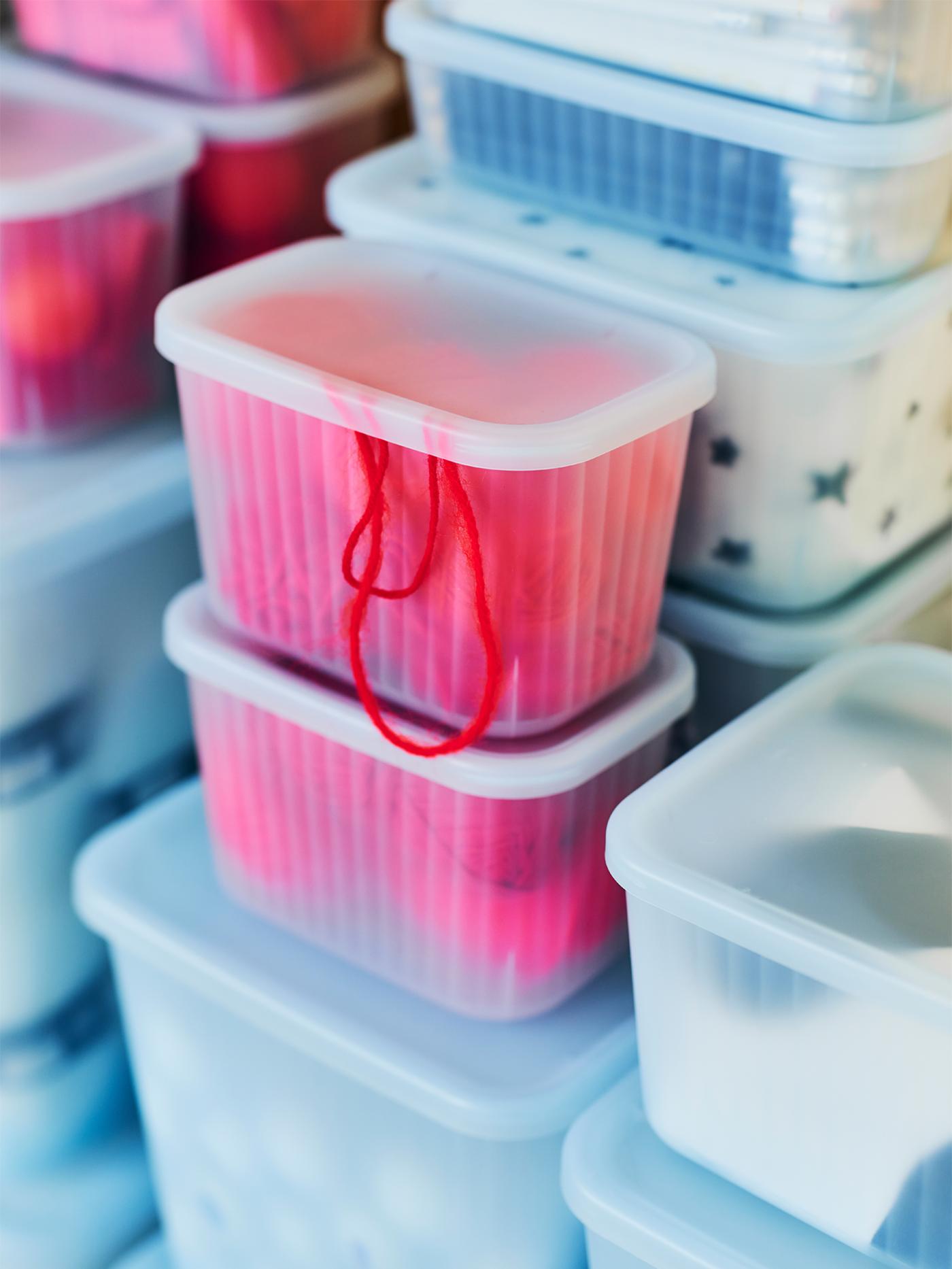A close-up of some semitransparent RYKTA storage boxes in different sizes with various objects inside.