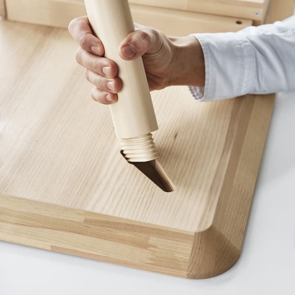 A close up of the bottom of the LISABO desk with a desk leg being put in, to show easy assembly.