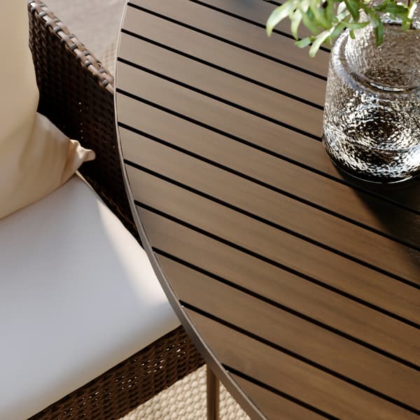 A close-up of the dark grey VITTSKÄR round table with soft lines and decorative fishbone pattern.