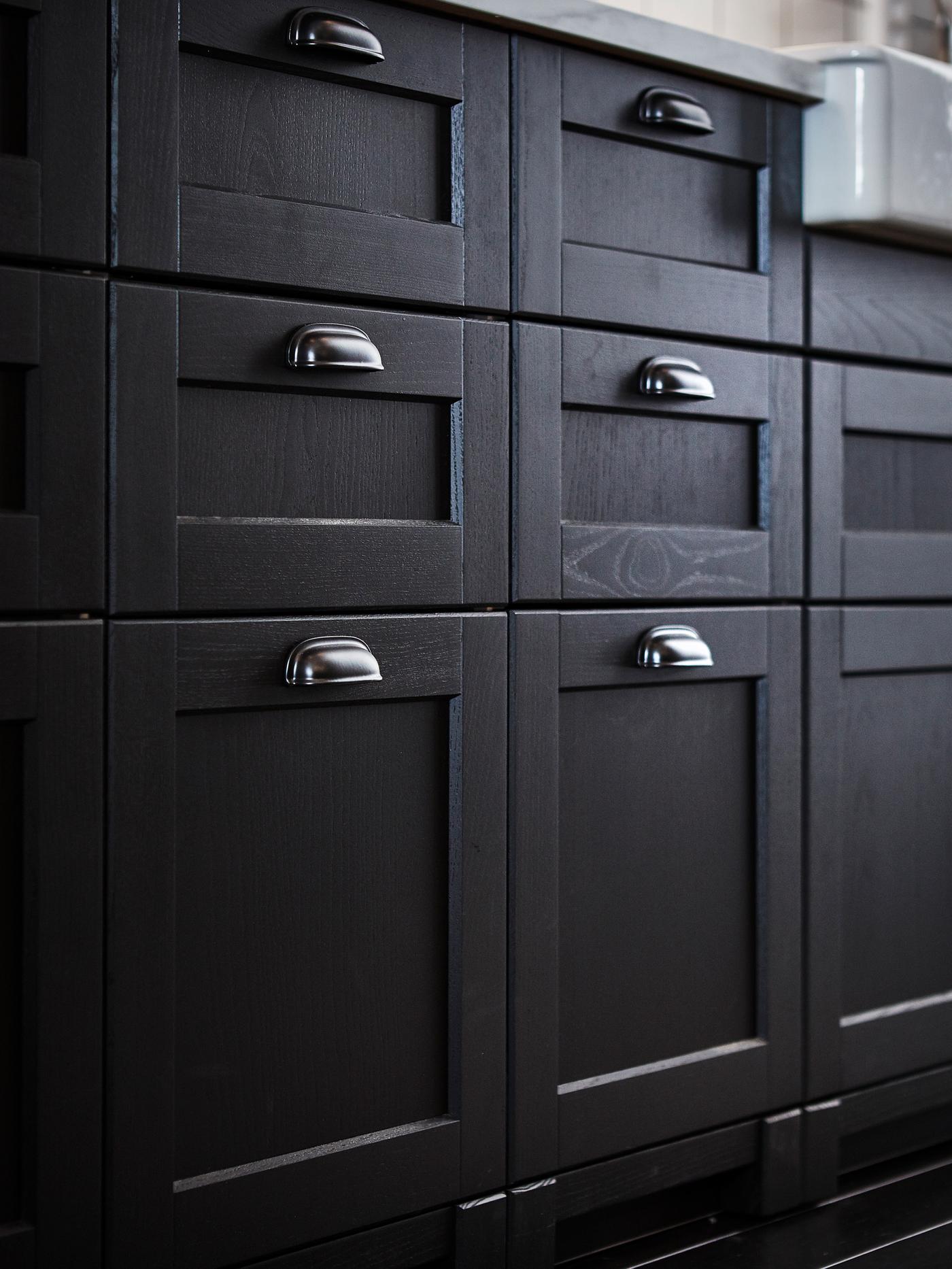 A close-up of traditional black LERHYTTAN drawer fronts with black ENERYDA cup handles in a kitchen setting.