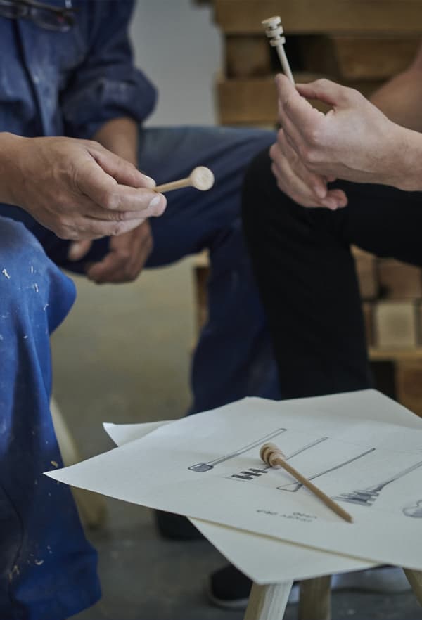 A close-up of two men holding wooden products being developed in a workshop.