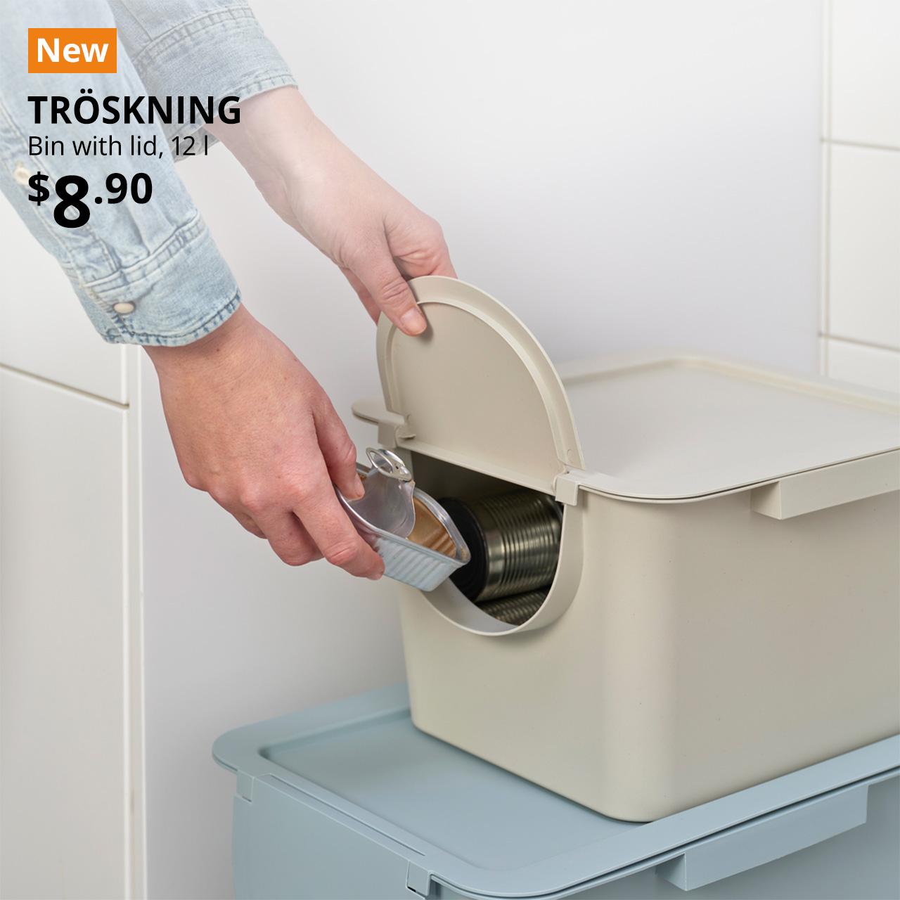 A close-up shot of a man disposing of clean, used tin into a light beige TRÖSKNING bin with a lid. A orange tag with white text that reads 'New', followed by black text overlay image that reads 'TRÖSKNING, Bin with lid, 12 l, $8.90'.