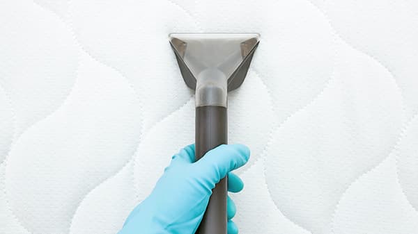 a close up shot of a person's vacuuming a mattress