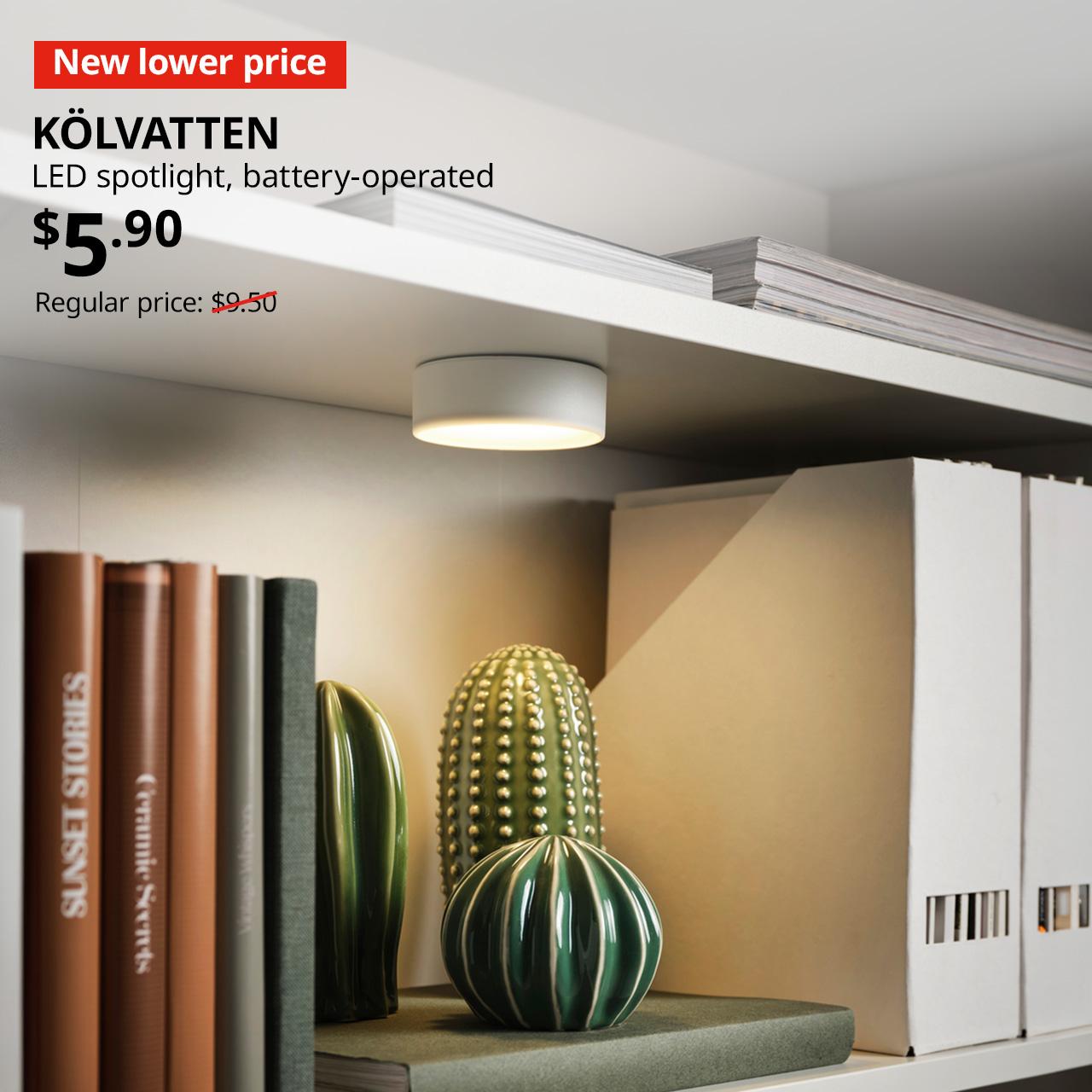 A close-up shot of a white KÖLVATTEN LED spotlight on a white BILLY bookcase. On the top left corner, a red tag with white text that reads "New lower price", followed by black text overlay image that reads "KÖLVATTEN, LED spotlight, battery-operated, $5.90, Regular price: $9.50".