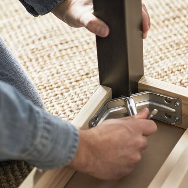 A close up shot of hands screwing in a table leg.
