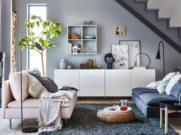 A closed storage cabinet system with white honeycomb patterned doors, and a pink sofa seat across from a blue sofa seat.