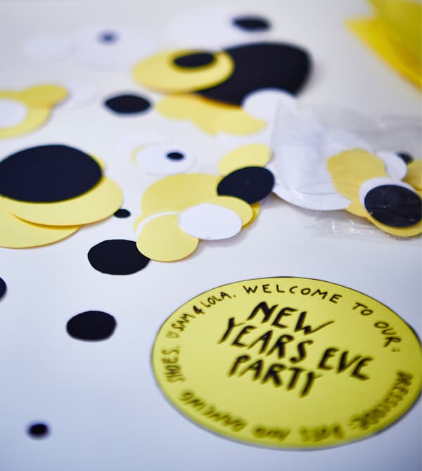 A closeup of big confetti dots cut from black, white and brigt yellow paper.