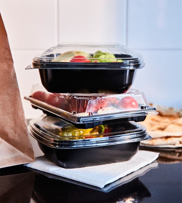 A closeup of takeaway containers are stacked on a countertop.