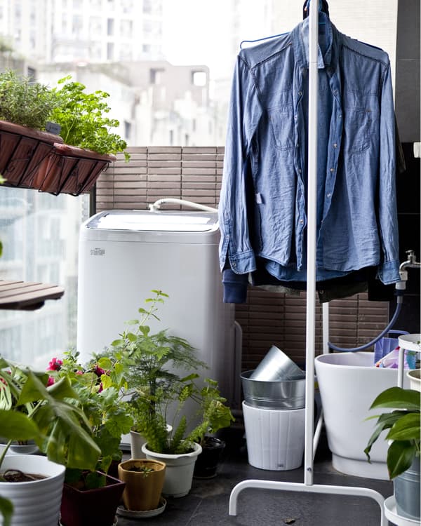 A clothes rail holds drying laundry on a city apartment balcony.
