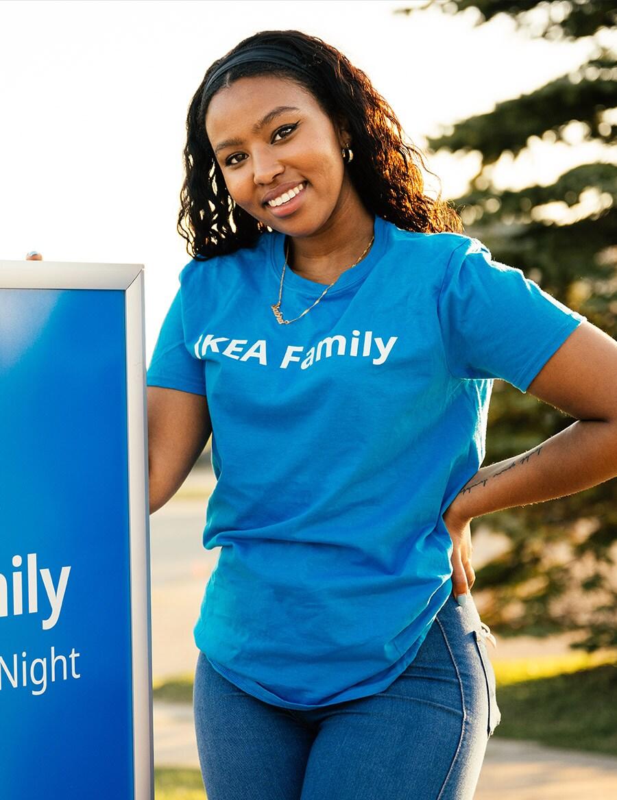 A co-worker from IKEA Vaughan stands beside an blue IKEA Family sign.