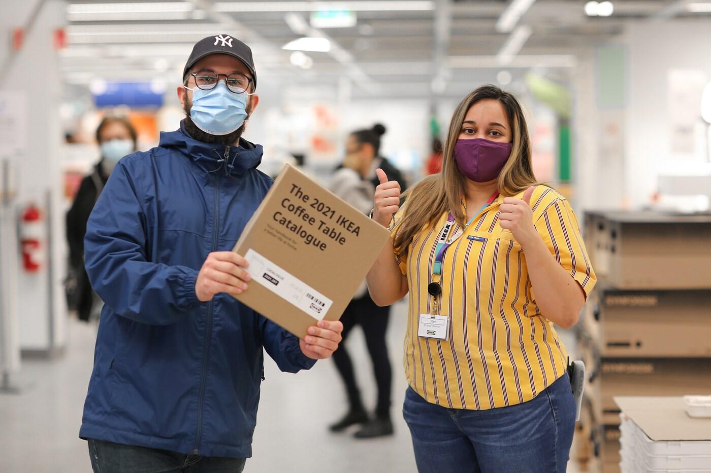A co-worker giving the thumbs up to an IKEA Family member holding their IKEA Coffee Table Catalogue