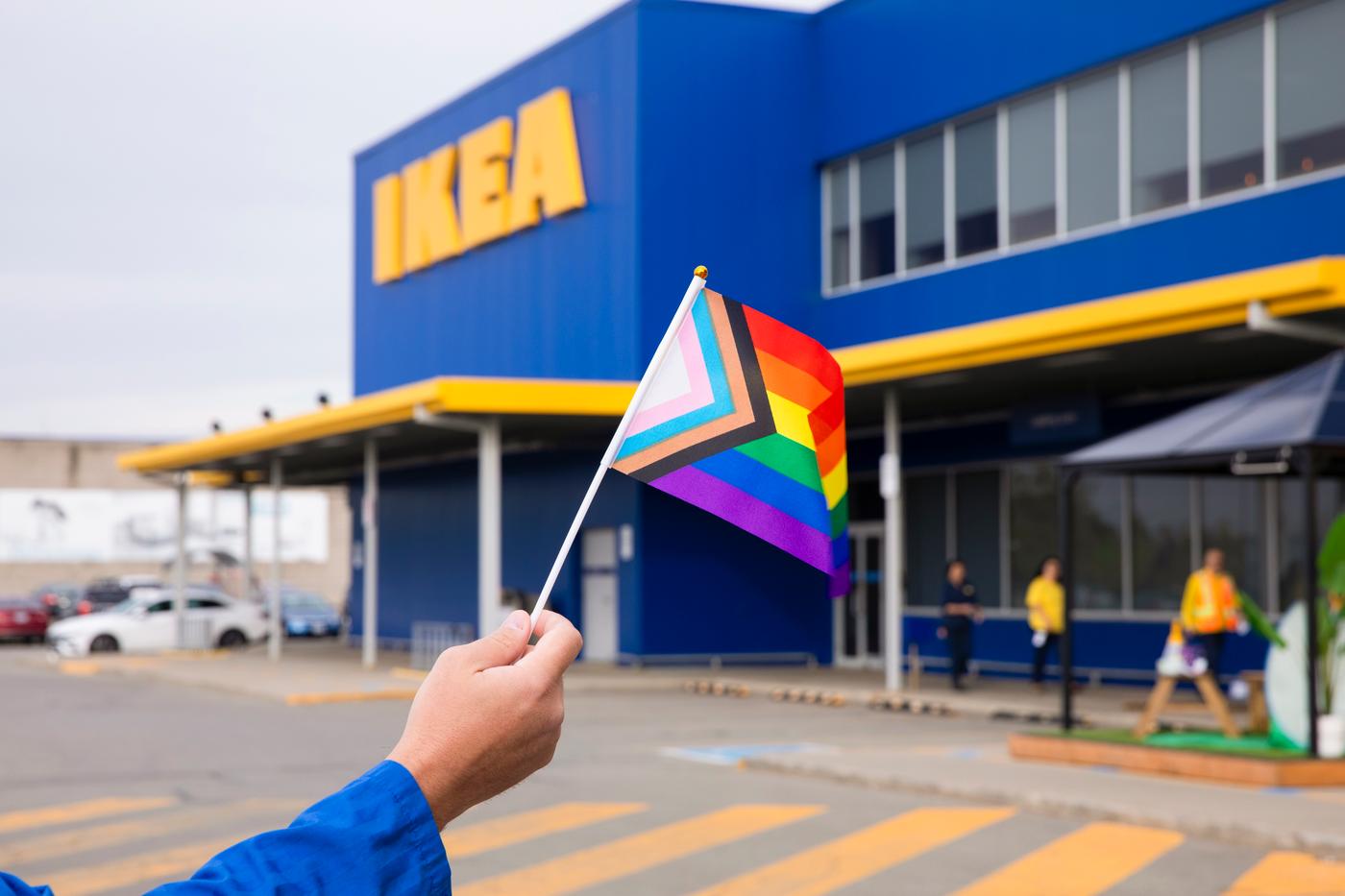 A co-worker is outside an IKEA store and waving a pride flag.