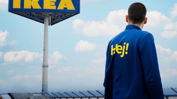 A co-worker stands in front of an IKEA sign, surrounded by solar panels under a clear sky