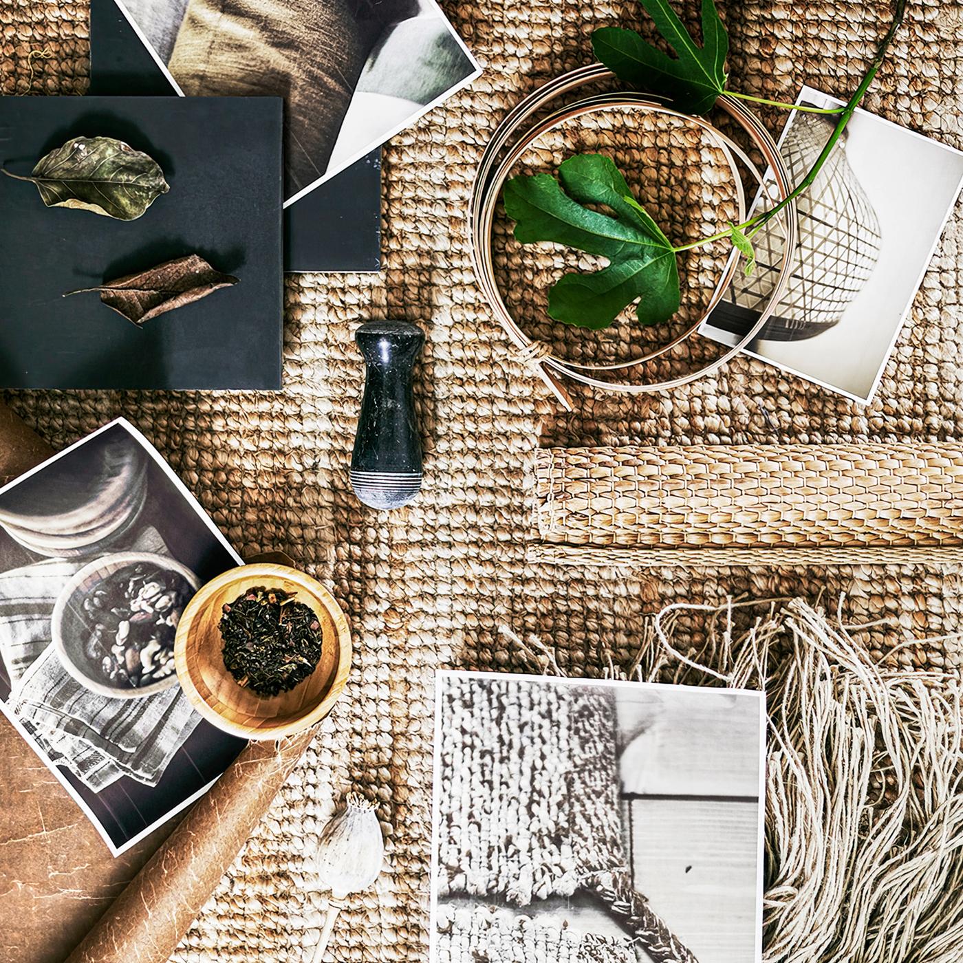 A coarsely woven rug with several printed pictures plus a variety of raw materials including leaves and wool.