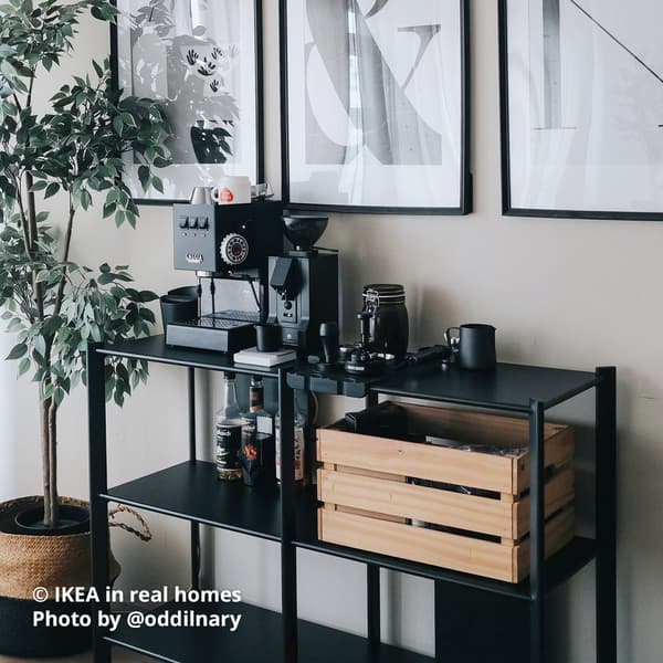 A coffee area within the living room area - A black JÄTTESTA shelving unit with coffee machine, coffee grinder and other equipments placed on the first tier of the shelving, while a KNAGGLIG wooden crate box is placed on the second tier with other coffee area essentials. Photo by instagrammer @nbhha for IKEA in real homes ©