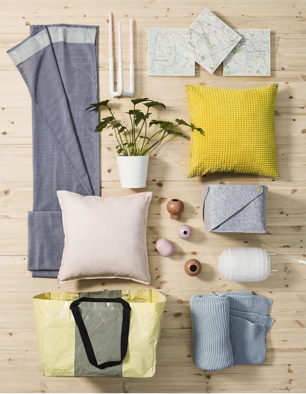 A collage of textiles and decorative objects in pastel shades on a wooden floor.