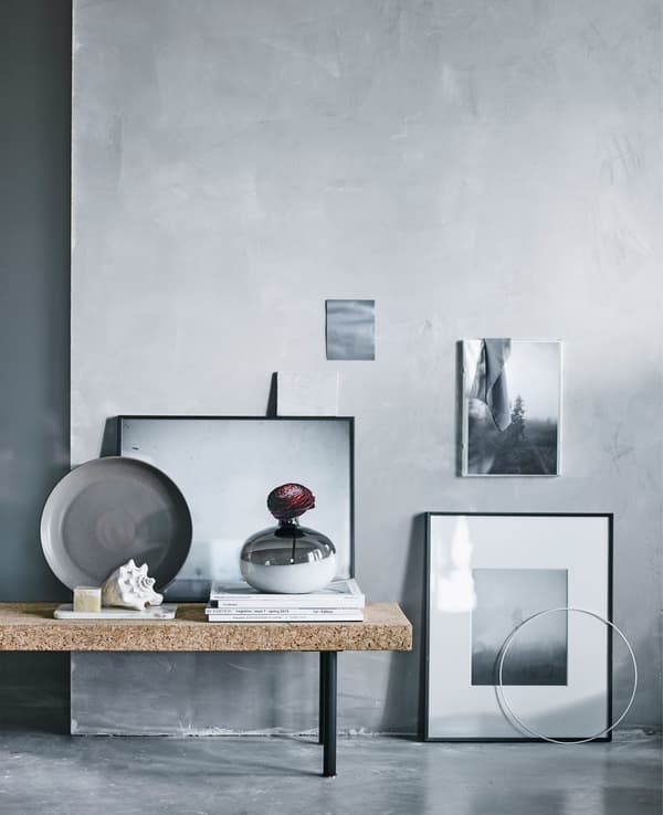 A collection of black and white pictures arranged by a grey wall.