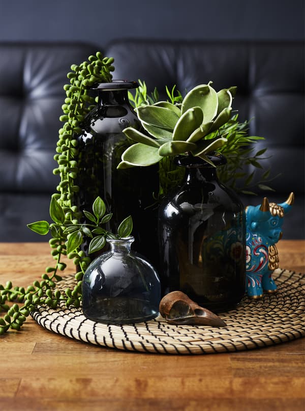 A collection of black vases filled with plants.