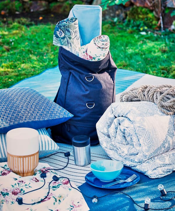 A collection of cushions, blankets and lamps placed on a picnic blanket.