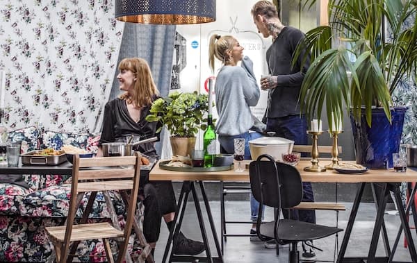 A collection of dining table and chairs with some people socializing together.