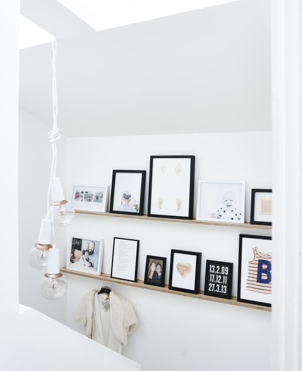 A collection of picture frames in different sizes placed on two mounted picture ledges at different heights.