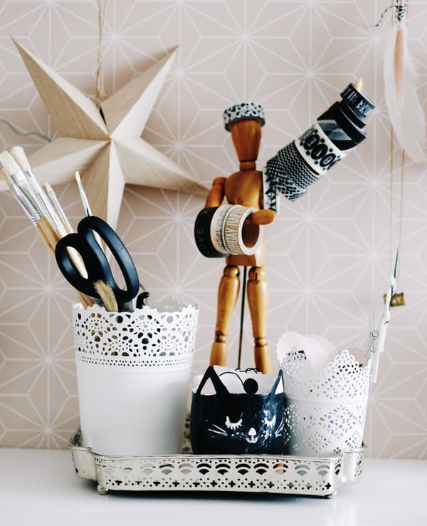 A collection of plant pots, tools and artist’s dummy on a desk.