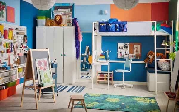 A colorful children's room with a white loft bed, an easel, a leaf-patterned rug and a blue children's desk chair.