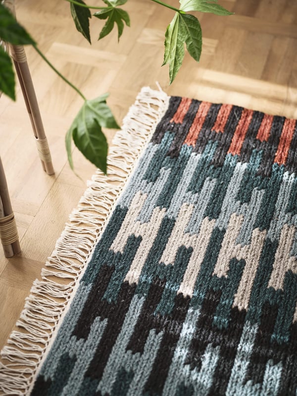 A colorful patterened rug on top of a wooden floor, linking to the rugs page