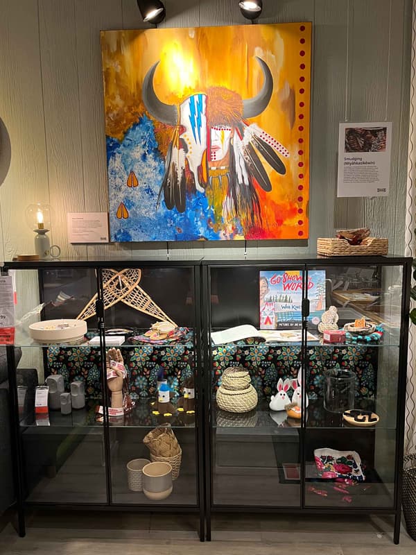 A colourful painting over a display cabinet.