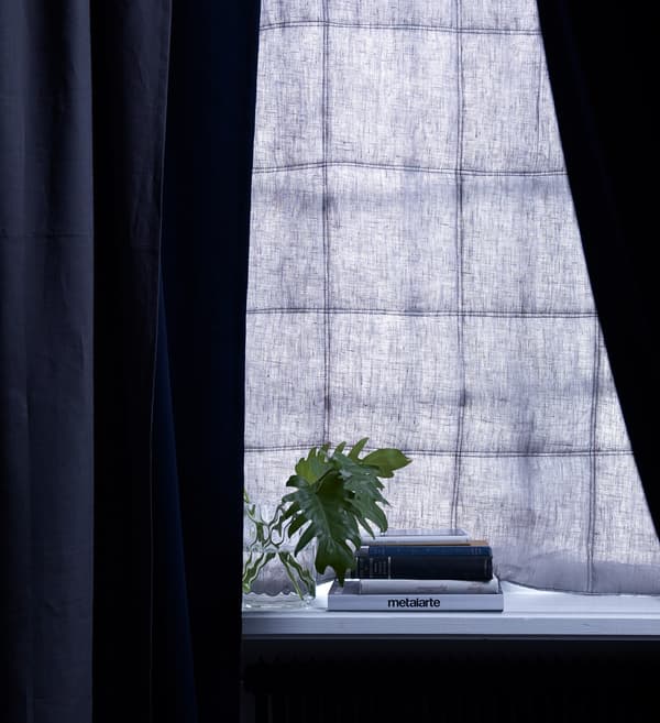 A combinación dunha cortina acolchada e un estor de cor azul escuro nas fiestras evita a entrada de luz e o ruído.