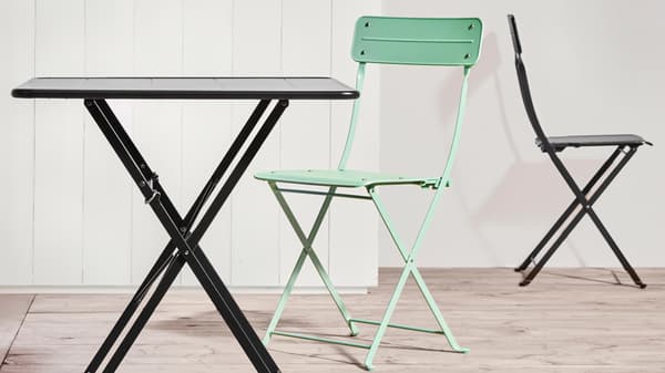 A compact and colorful bistro set featuring a black folding table and mint green and black folding chairs – perfect for a small balcony or patio.