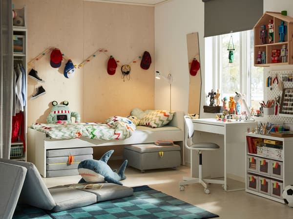 A contemporary children's bedroom with wood clad walls and a blue rug and the SLÄKT bed frame, foldable mattress and seat module.