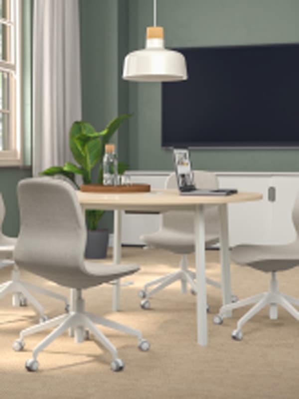 A contemporary office with green walls, office chairs are placed around a MITTZON conference table in white/birch veneer.